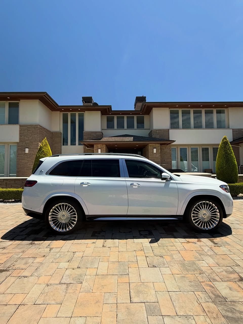 Side profile of a freshly detailed white Maybach SUV on a Peninsula driveway